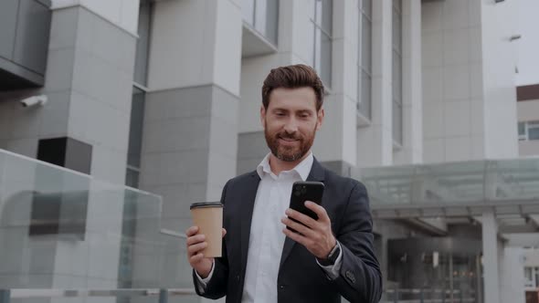 Confident Businessman Walks in the City with a Phone in His Hands and Uses an Application for
