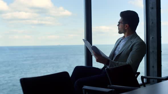 Businessman Reading Contract Papers at Sea View