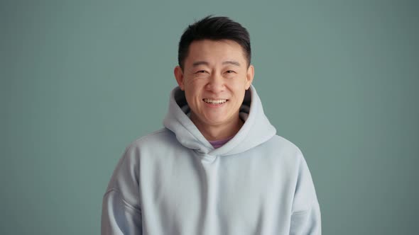 Laughing Asian man wearing hoodie looking at the camera