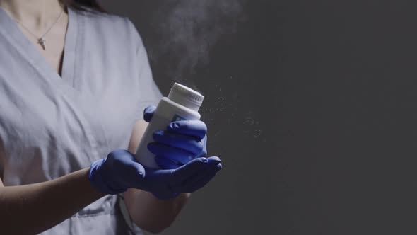 Female Master's Hands in Gloves Hits a Jar of White Powder Flying in Air