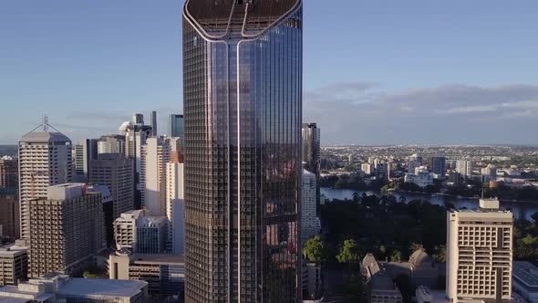 Aerial slow rising shot of tall city building along river Brisbane, Queensland