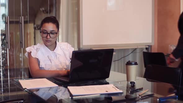 Two Young Business Women Discuss a Business Project in an Office Using a Computer