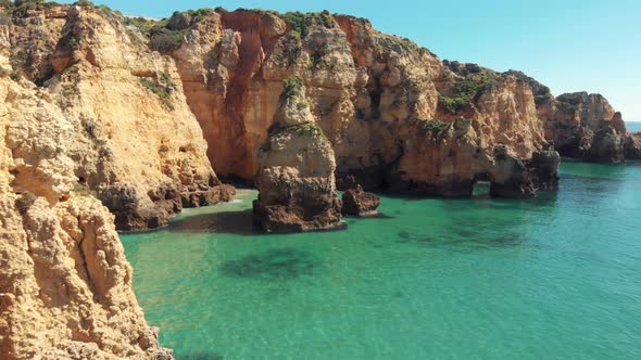 Craggy cliffs jutting out of crystal clear waters of the Algarve Sea, in Lagos, Portugal