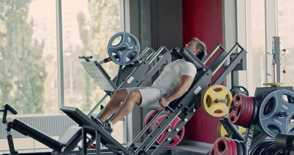 Sporty Man Doing Exercises with Leg Press Machine at Fitness Gym, Hard Squats Workout
