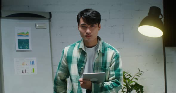 Young Asian Man Smiling Looking at Camera While Standing with Tablet in Office