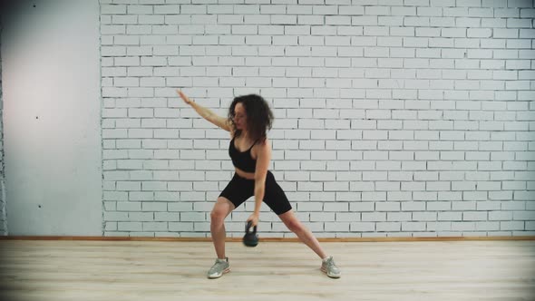 Workout in Sports Studio  Young Woman with Curly Hair Training Her Hands By Working with the Weight