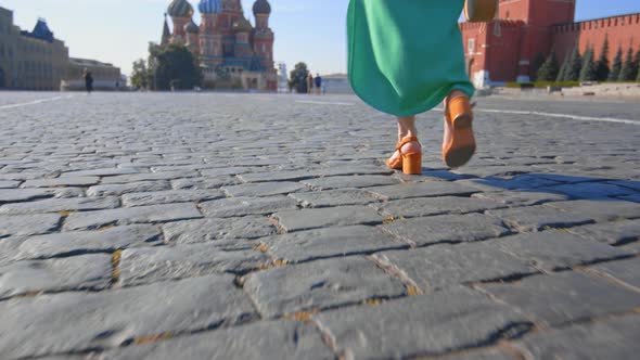 A girl in a green dress walking along the sett in Red Square