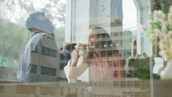 Happy diverse couple spending time together at cafe, drinking coffee and talking