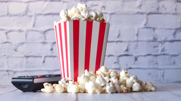 Close Up of Popcorn in a Container and Tv Remote on Table 