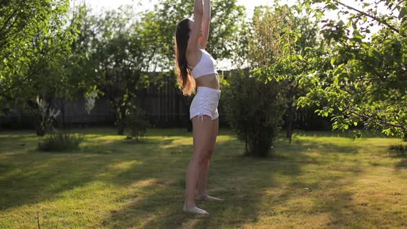 Young Woman Doing Yoga Asana Bridge Pose on Green Grass