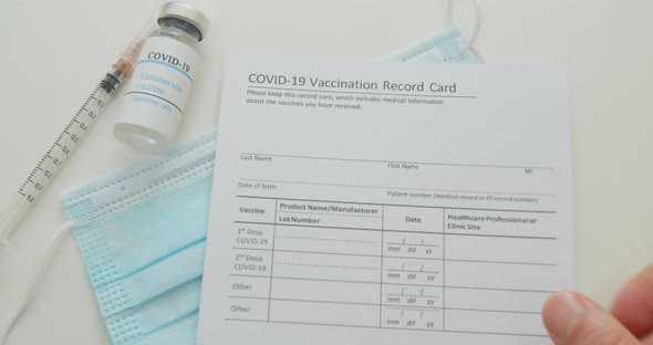 Medical Mask and COVID19 Vaccine Doctor Hand Put Vaccination Record Card