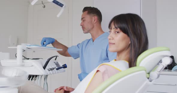 Portrait of smiling female patient with caucasian male dentist at modern dental clinic