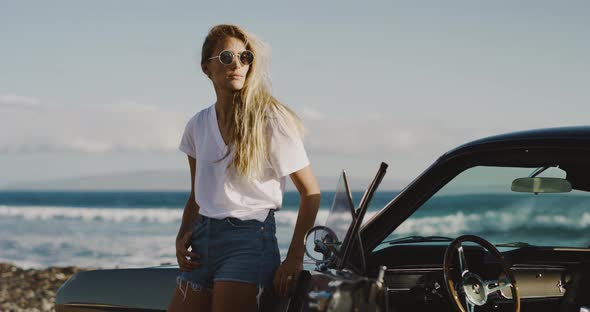 Beautiful woman posing with a vintage sports car