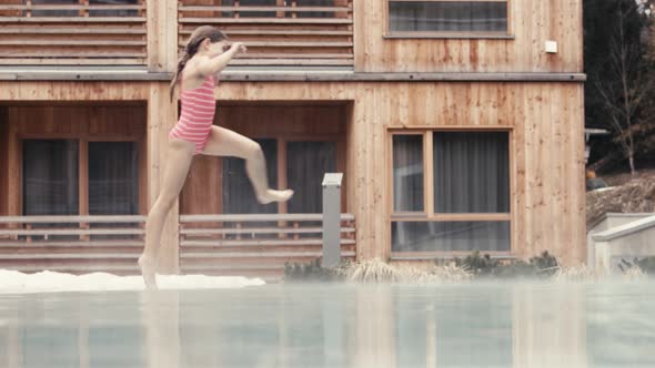 Smiling girl jumping into swimming pool