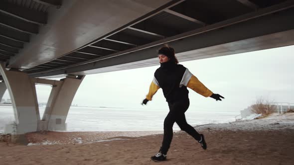 Female Athlete Performing Aerial Cartwheel on Shore of Frozen Lake