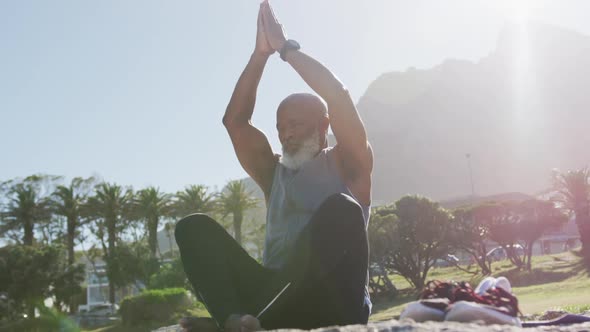 Senior african american man exercising stretching on rocks by the sea