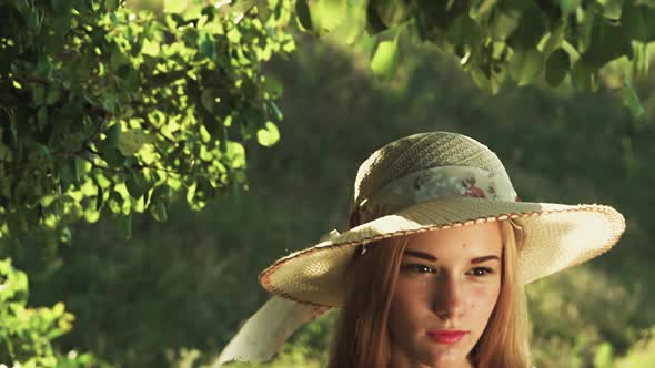 Girl in a Hat Poses for Cameras in a Green Forest. Slow Motion