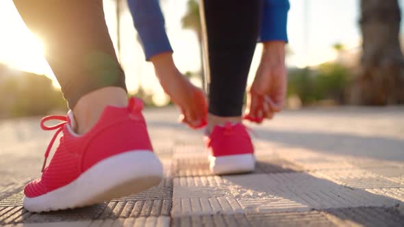 Close Up of Woman Tying Shoe Laces and Running Along the Palm Avenue at Sunset