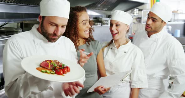 Team of chefs holding food plate in commercial kitchen