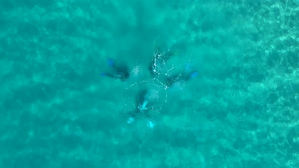 Looking down at four scuba divers underwater with bubbles breaking the ocean surface