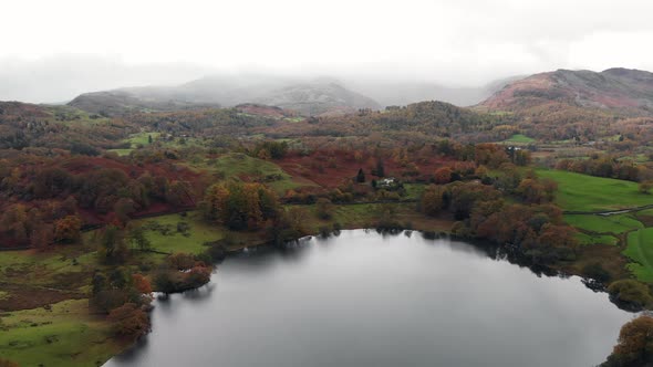 Aerial footage above Loughrigg Tarn in Cumbria looking over to Windermere.