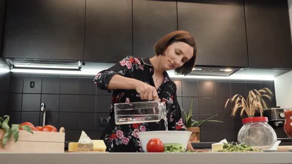 Woman cooking dough for pizza at home kitchen. Female adding water to flour