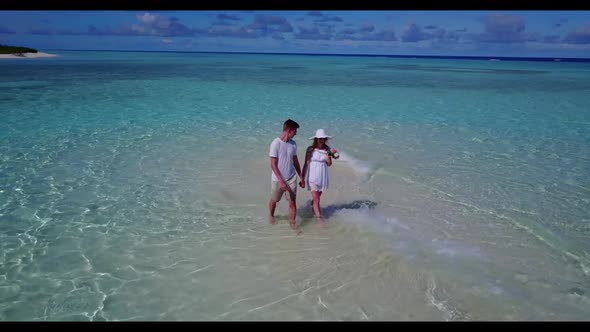 Two people happy together on perfect lagoon beach wildlife by aqua blue sea with bright sand backgro