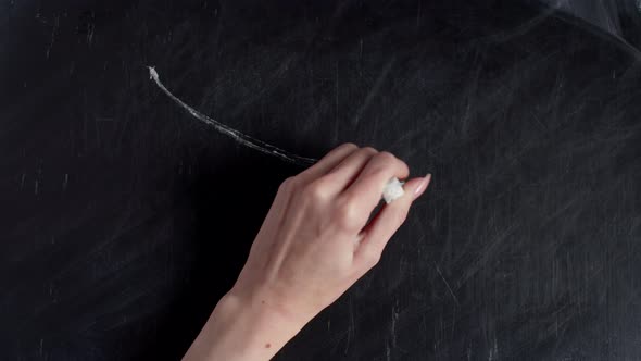 Human Hand Draws Down Arrow and Phrase Crisis on Chalkboard