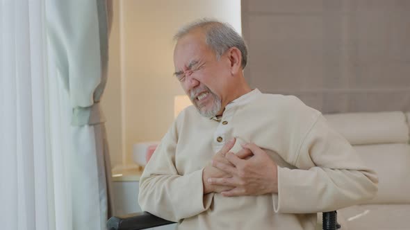 Asian Senior Elderly disabled man on wheelchair with chest pain suffer from heart attack at home.