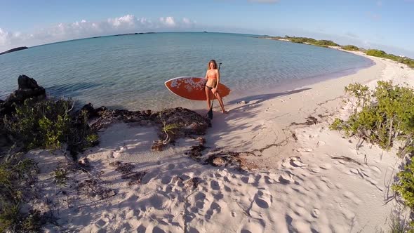 Aerial portrait of young woman about to go sup standup paddleboarding.