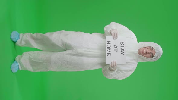 Full Body Of Asian Man Wear Uniform Ppe And Holding Stay At Home Sign In Green Screen Studio