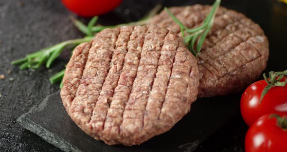 Raw Burger on a Board with Rosemary and Tomatoes Rotates. 