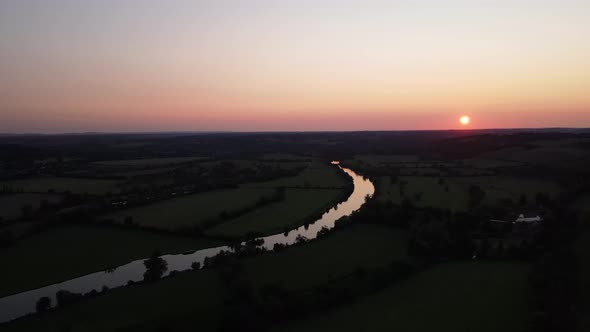 River Thames with bright golden sun over horizon and colored sky at sunset, Mapledurham in UK. Aeria