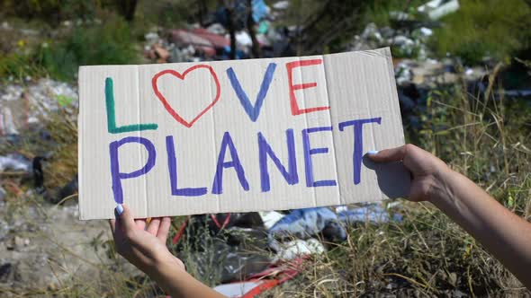 Love Planet Phrase on Cardboard in Person Hands Against Landfill Background