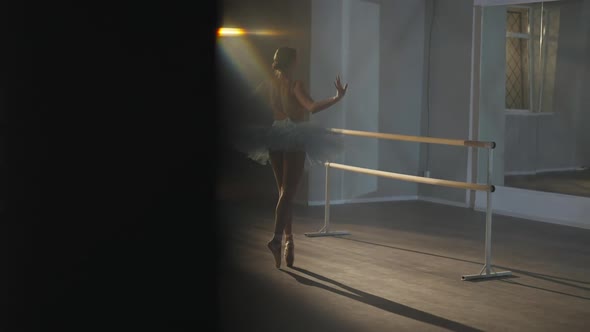 Wide Shot of Slim Graceful Ballerina Rehearsing Spinning on Tiptoes in Dancing Studio Spotlight