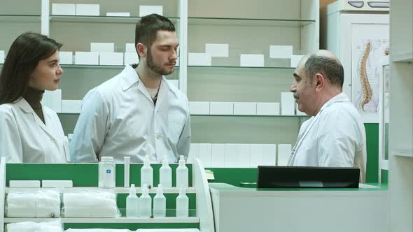 Elderly Pharmacist and Assistants Talking Seriously at Farmacy Reception