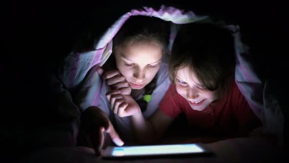 Small Girls Play Online Games on Tablet under Blanket at Night