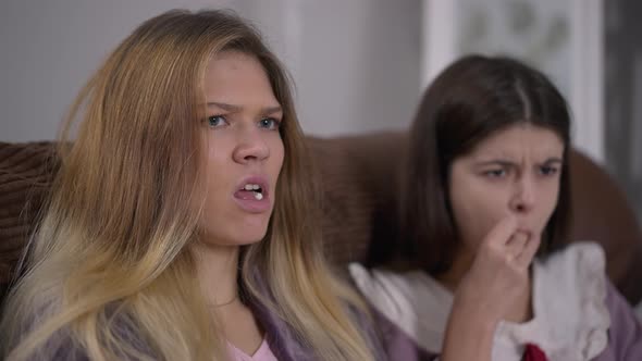 Closeup Portrait of Beautiful Young Woman Watching Show on TV with Friend Throwing Popcorn Rolling