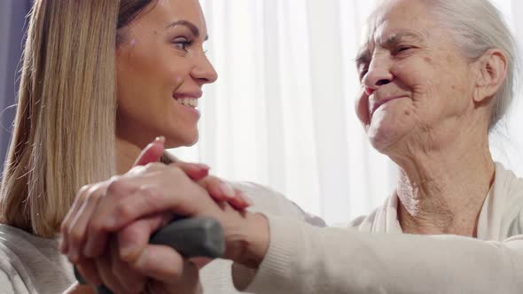 Happy Woman Holding Hands and Talking with Elderly Grandmother 