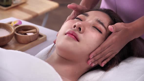 Young Asian woman getting facial massage in luxury spa salon