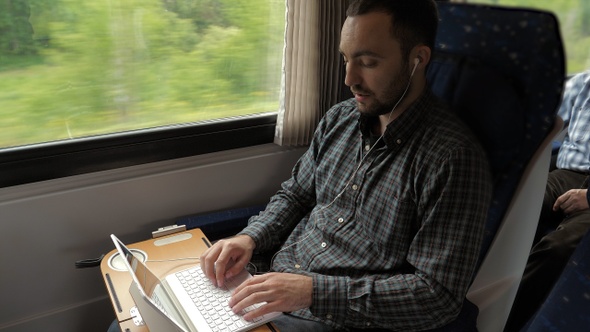 Creative man designer working on his laptop computer in a train.