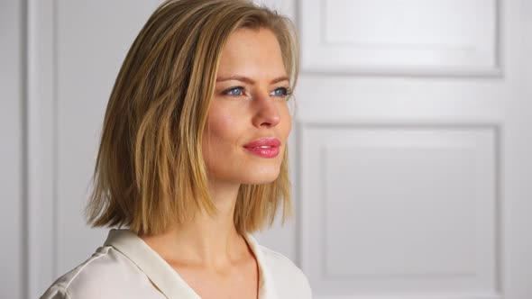 Model with Sexy Eyes Arranges Hair and Looks into the Distant Smiling