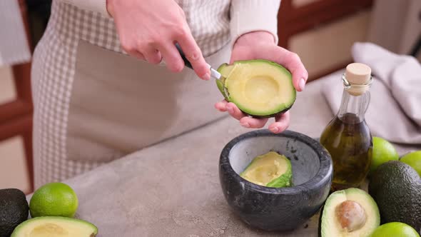 Woman Takes Out the Pulp of the Ripe Avocado From the Peel with a Spoon at Domestic Kitchen