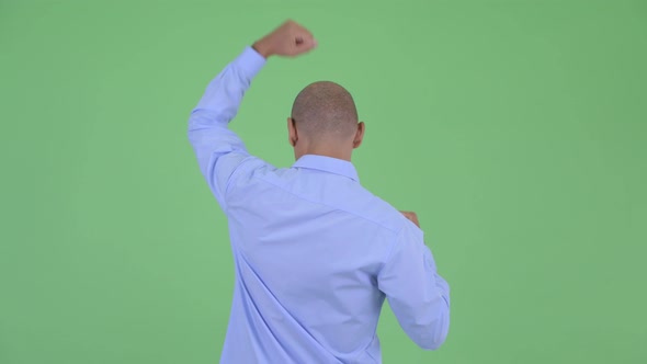 Rear View of Happy Bald Multi Ethnic Businessman with Fists Raised