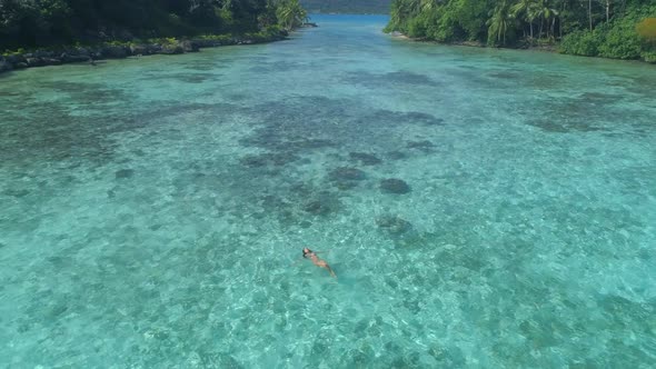 A woman swimming in a tropical green lagoon in Bora Bora tropical island