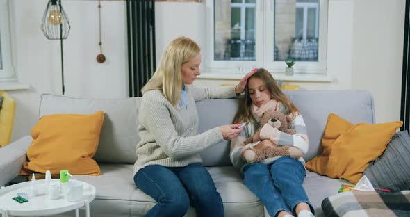 Mother Checking Temperature on Thermometer After Measuring of Her Sick Unhappy Teen Daughter