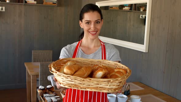 Portrait of female baker holding baguettes in basket