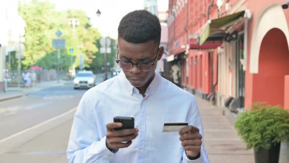 African Man Making Successful Online Payment on Smartphone in Street