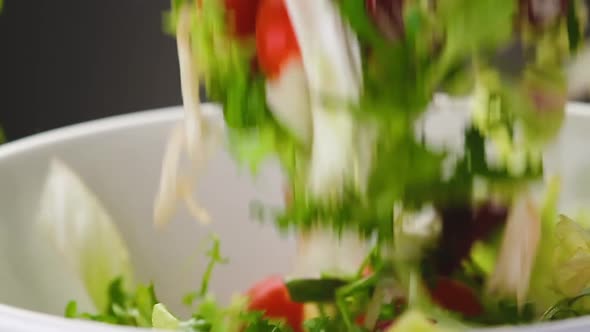 Fresh Salad Falling Into Bowl on Black Background