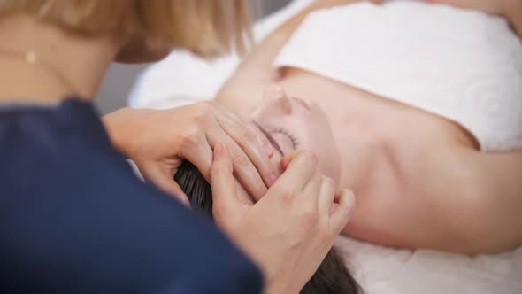 Massage Session  Young Woman Pushing Her Fingers on the Forehead of Her Female Client